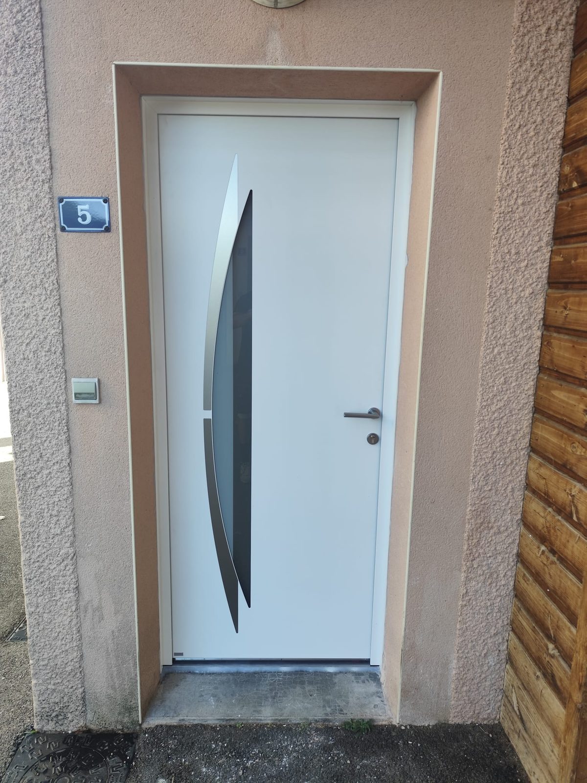 Nouvelle porte d'entrée design blanche avec poignée inox brossé, posée par Monts Renov à Thurins