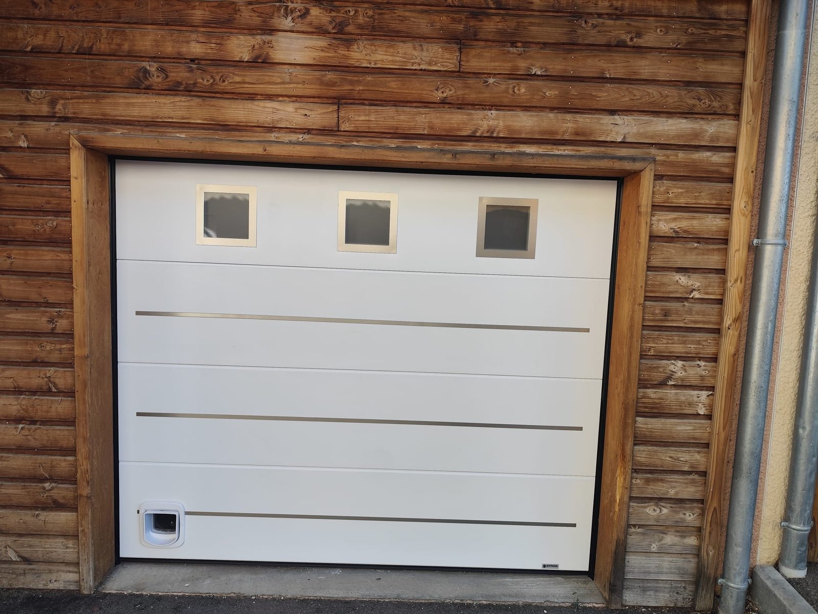 Porte de garage sectionnelle design avec hublots et chatière, Thurins