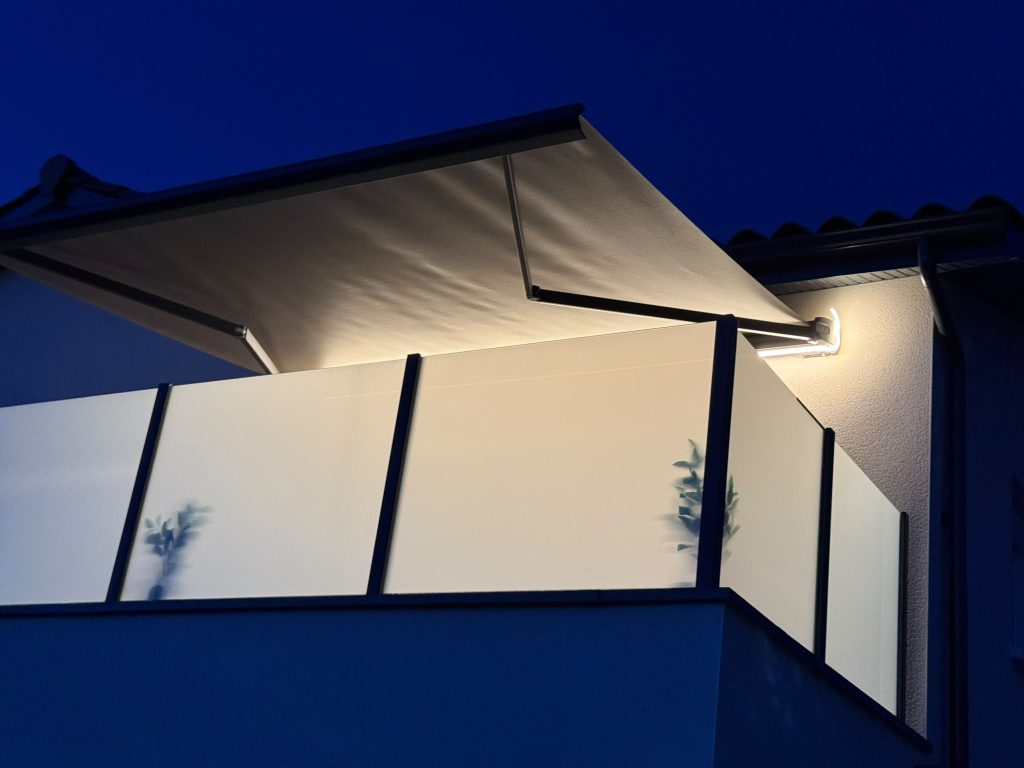 Store banne déployé avec coffre intégral et armature aluminium, vue de nuit sur une terrasse à Brindas